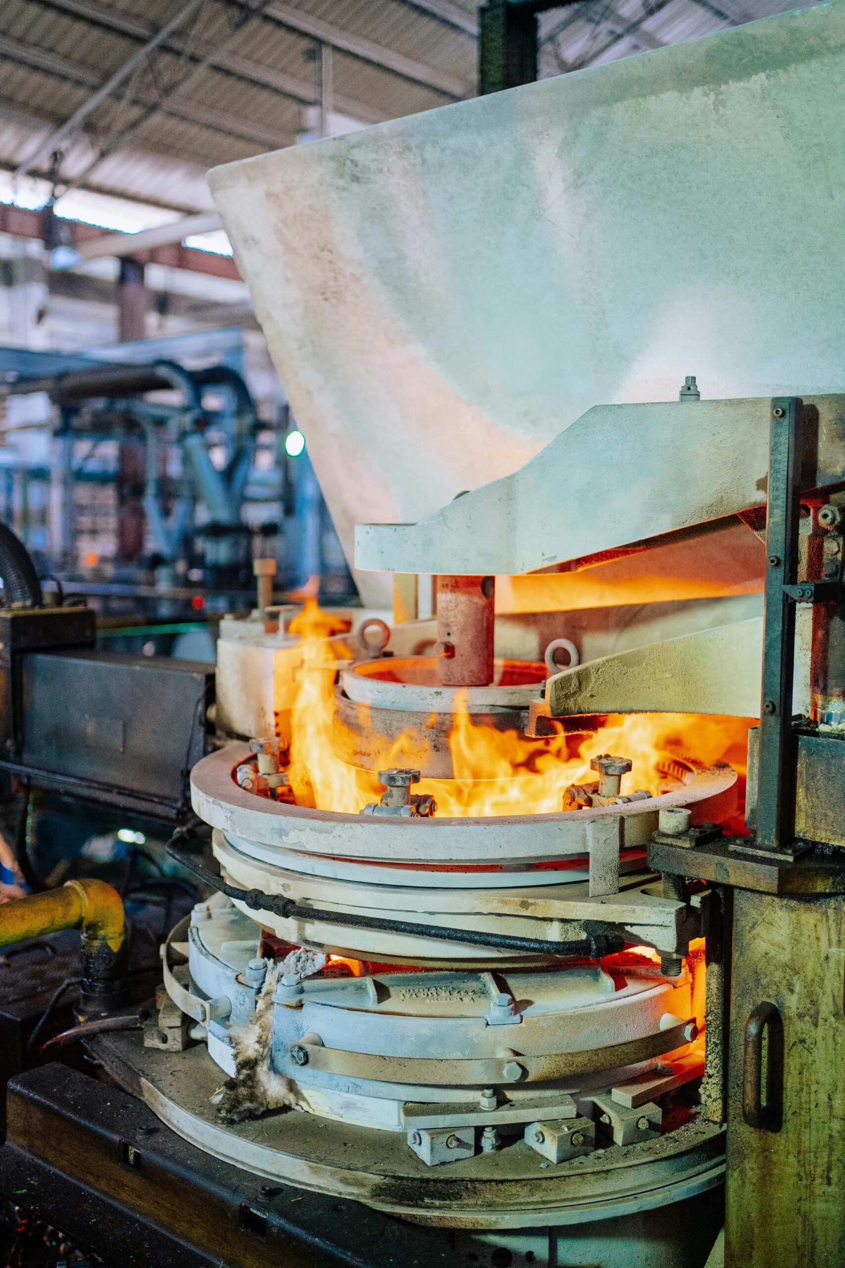 Fiery glass production process inside a factory with intense heat and machinery.